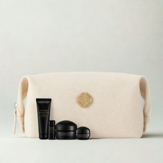 A beige canvas cosmetic pouch with a gold-tone logo medallion, displayed with four black Shiseido Future Solution skincare bottles and jars in front of it on a light gray background.